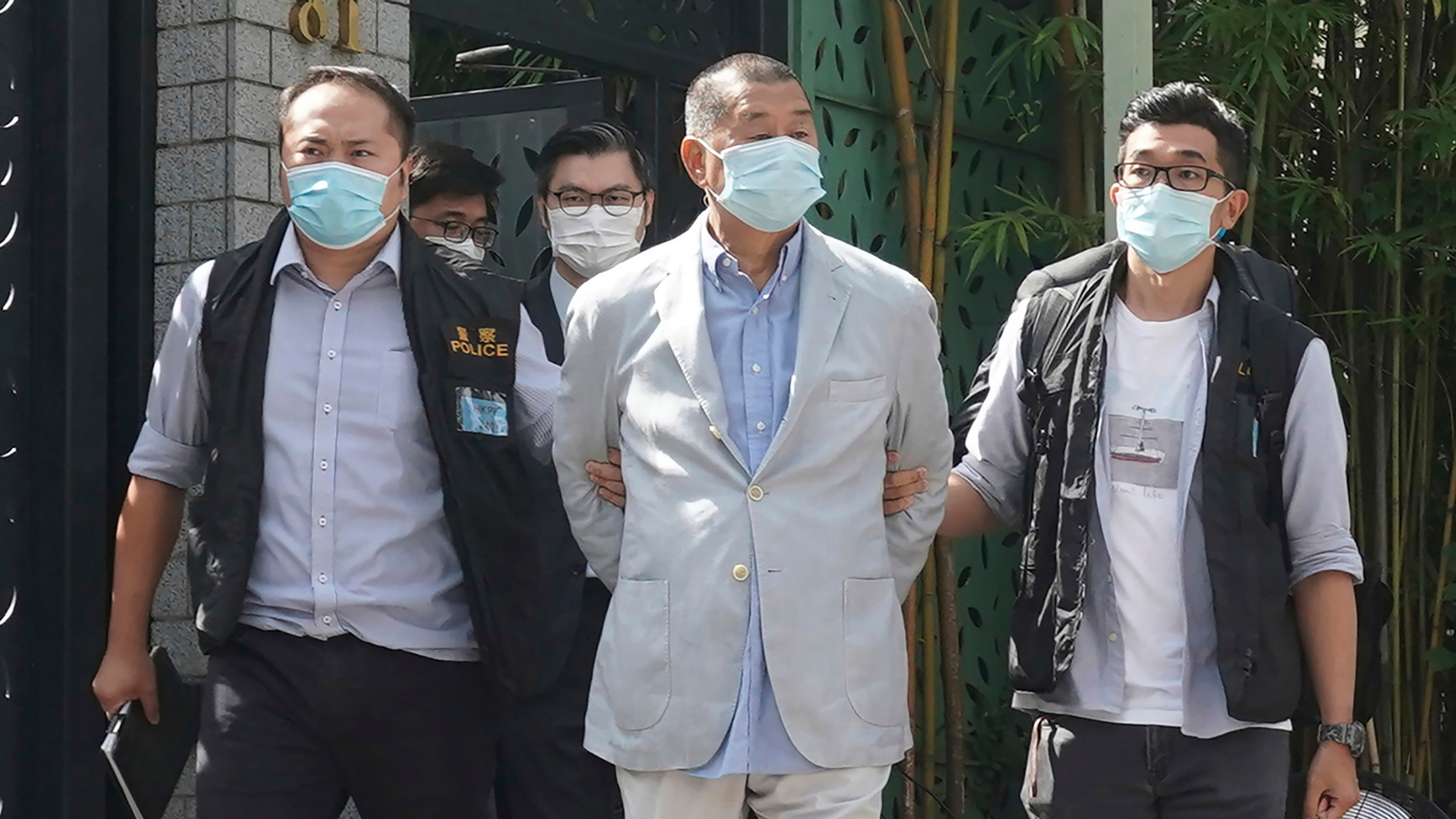 0113 潘 Hong Kong media tycoon Jimmy Lai, center, who founded local newspaper Apple Daily, is arrested by police officers at his home in Hong Kong, Aug. 10, 2020.AP25348133892831