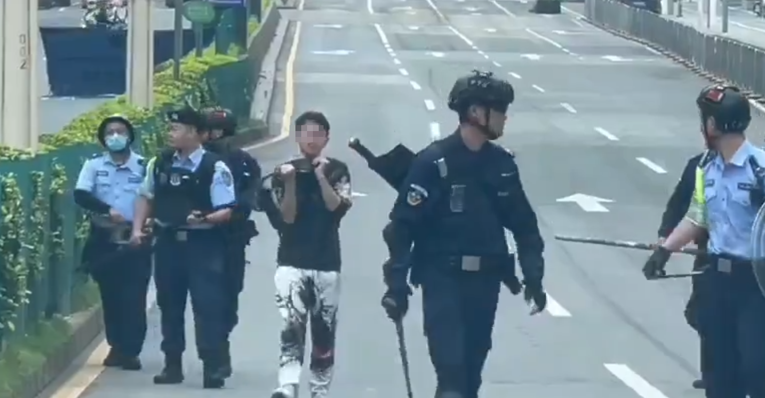 廣東東莞一名涉嫌持菜刀搶劫的男子,在虎門鎮虎門大道路中央手持菜刀架在自己的頸前方,與現場全副武裝的警方對峙,他最終被制服逮捕。(影片截圖)