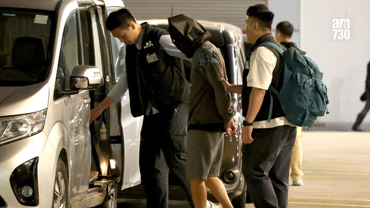 潛逃37年的疑犯，被黑布蒙頭和雙手扣上手銬帶離警署。(鍾式明攝)