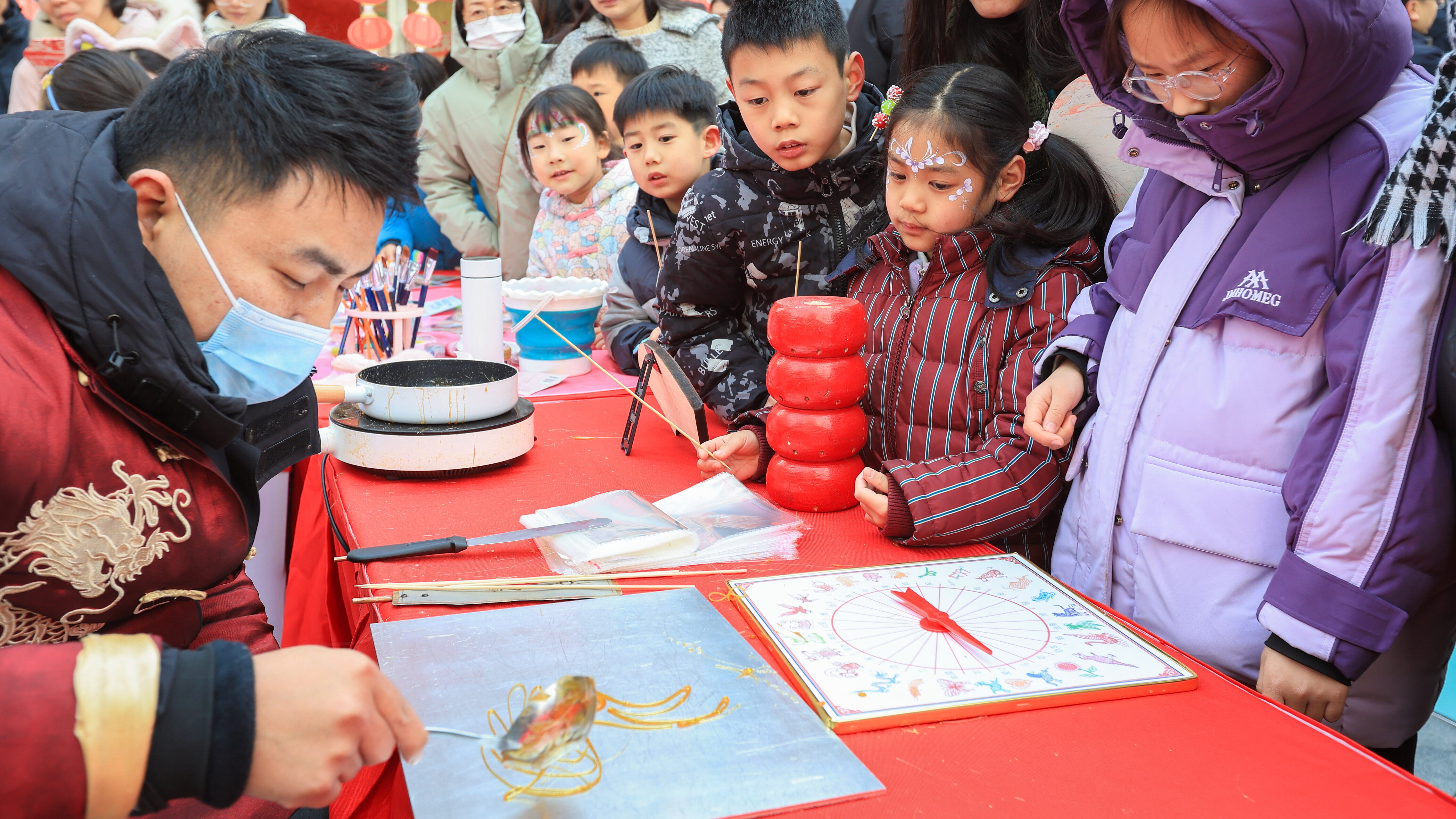 小朋友在南京舉行的「樂購新春 蘇品蘇貨」年貨大集上觀看糖畫。(新華社)