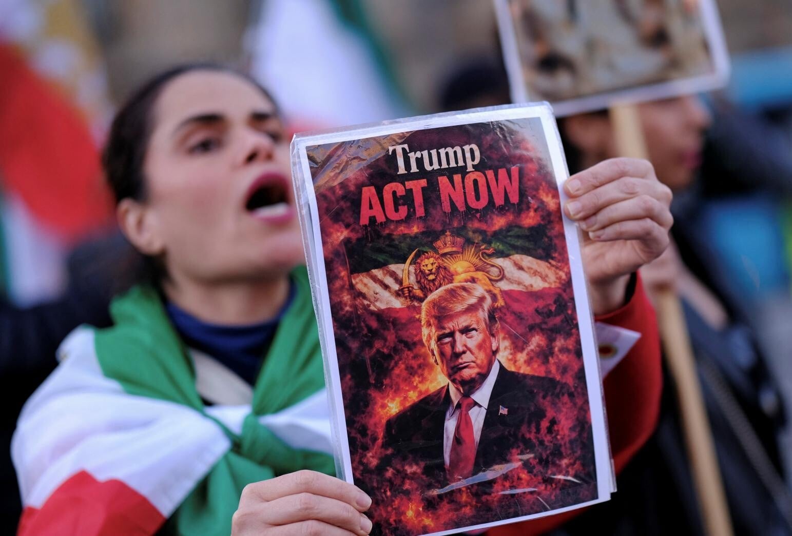 2月21日,在西班牙巴塞隆納,一名伊朗人手持印有美國總統川普的標語參加抗議伊朗政府的示威。該標語呼籲川普立刻行動。(圖/路透社)