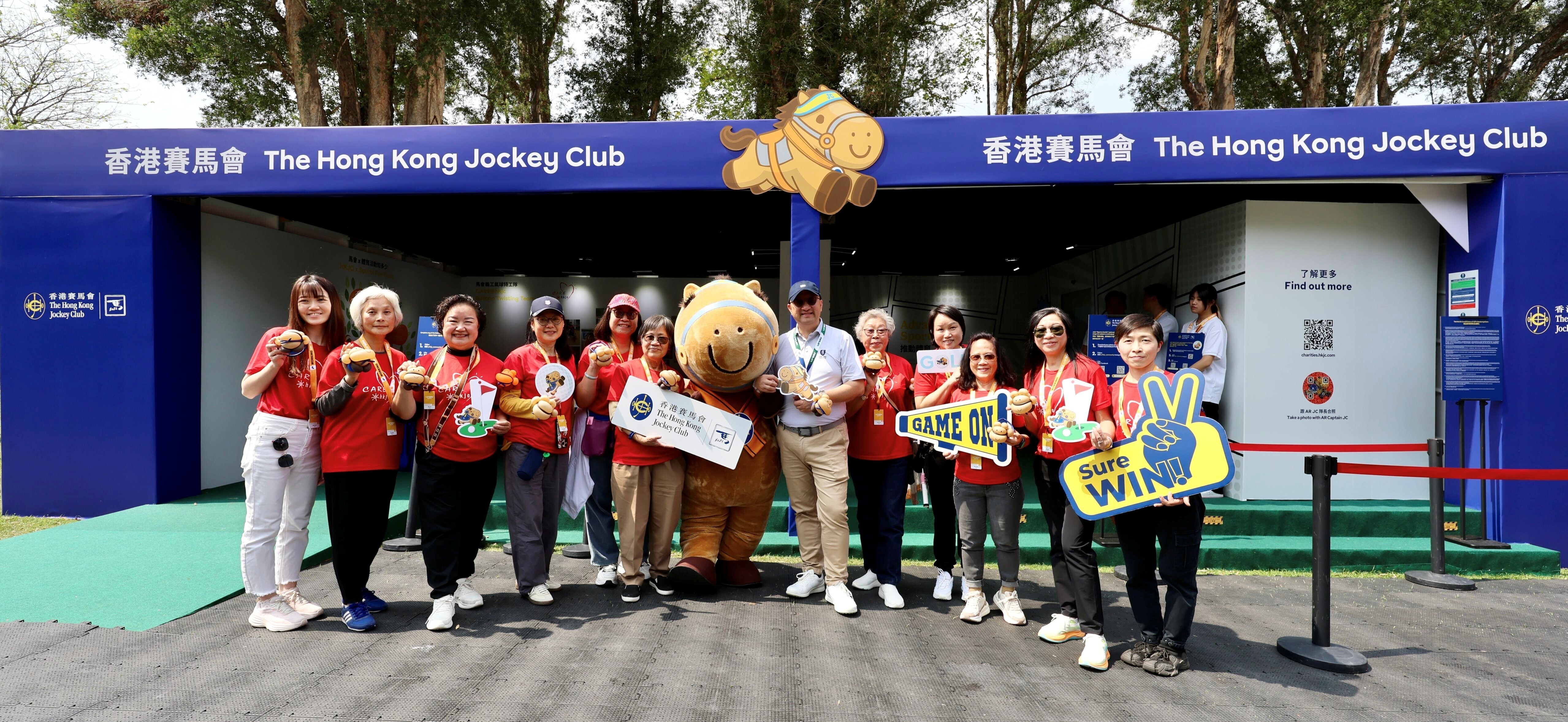馬會義工隊 CARE@hkjc 成員在觀眾村製作氣球公仔,並與馬會公司事務執行總監 譚志源(右六)合照。