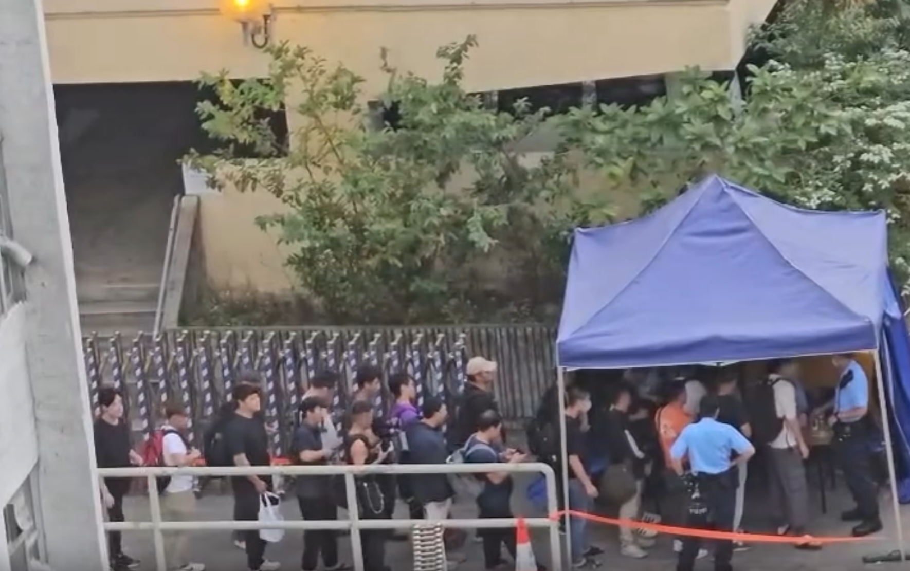 大埔宏福苑五級火|近日有網民於社交平台上載影片,拍攝到10多名工人在警崗前排隊登記,待警員記下資料就可以離開(影片截圖)