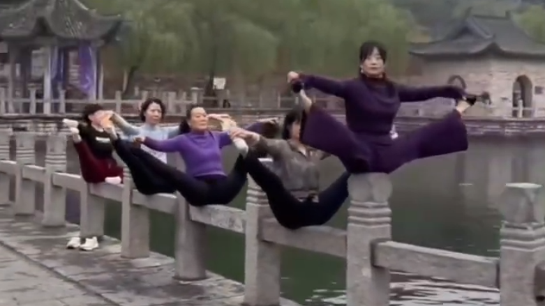 河南新鄉百泉風景區有多名女子在湖邊石欄杆上進行高難度瑜伽動作，包括凌空分腿及倒立等。(影片截圖)