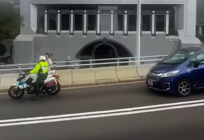 中環花園道天橋有女子疑誤入沒有行人路的天橋路壆位,正當她前往金鐘方向之際,有騎電單車的交通警駛至「護航」(車cam L(香港群組)FB)
