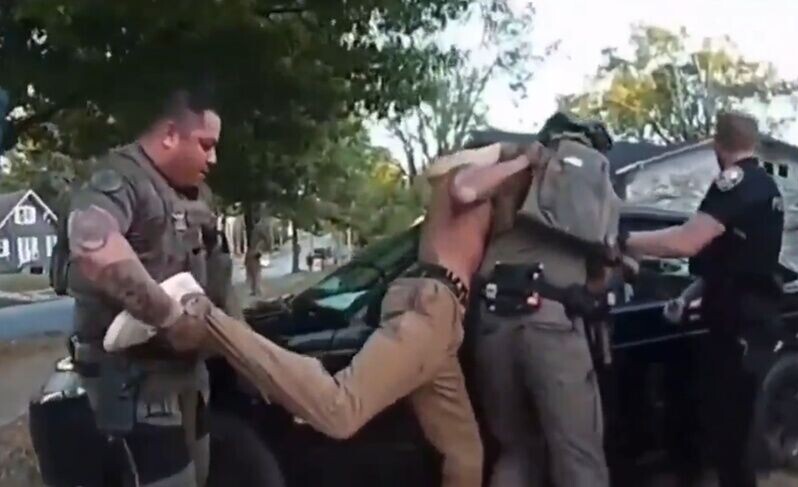 3名警員將David壓制於一輛車前,David仍企圖掙扎。(X)