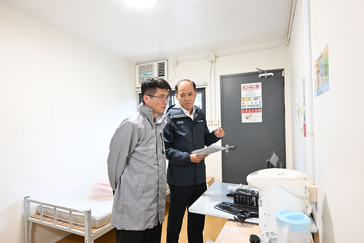 衞生防護中心緊急應變及項目管理處主任梁耀康(左),與民眾安全服務處總參事梁冠康(右)巡視竹篙灣社區隔離設施。(政府新聞處)