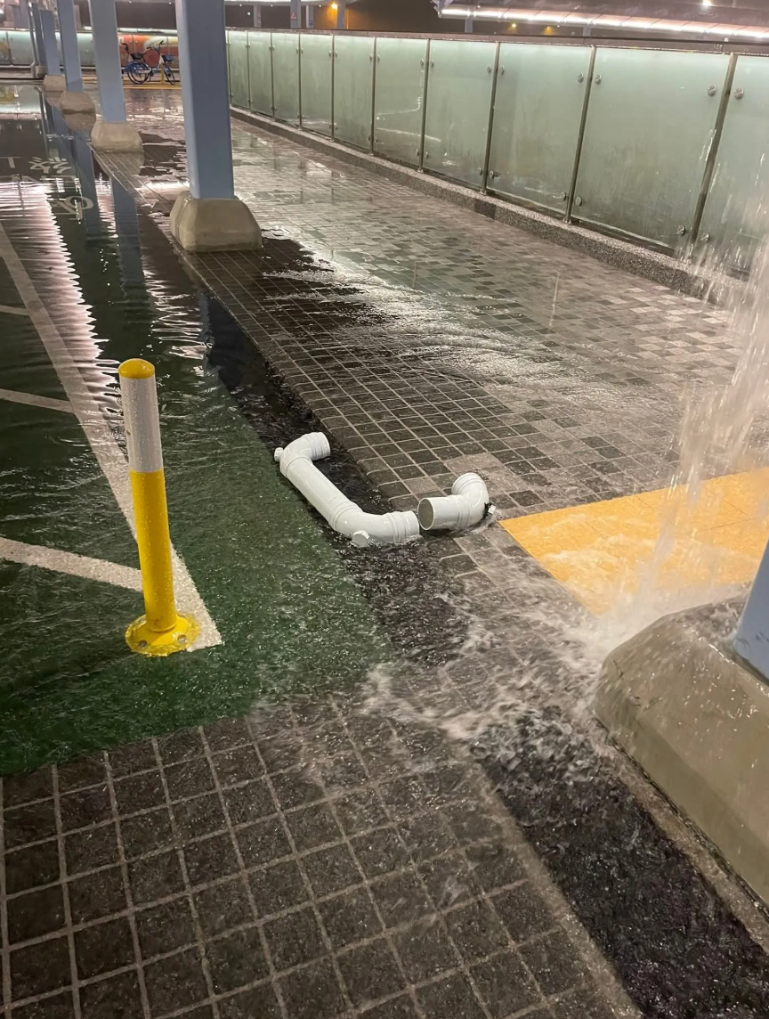 黃雨下粉嶺龍躍頭交匯處環形行人天橋,上蓋的排水膠喉鬆脫,雨水如「水舞間」傾瀉,工人搶修。(Threads)