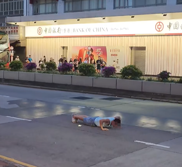 一名男子在深水埗長沙灣道207號對開的馬路中線「玩命」做掌上壓,過程中有巴士在旁邊右線擦身而過。(影片截圖)