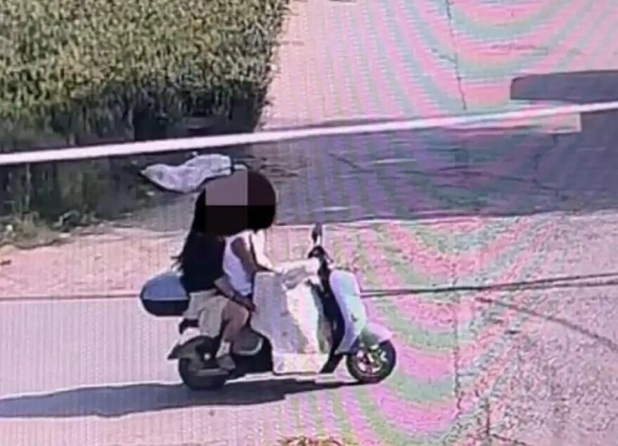 一對男女將「鋤頭」藏擋風布下騎車離開。(圖/翻攝大河報)