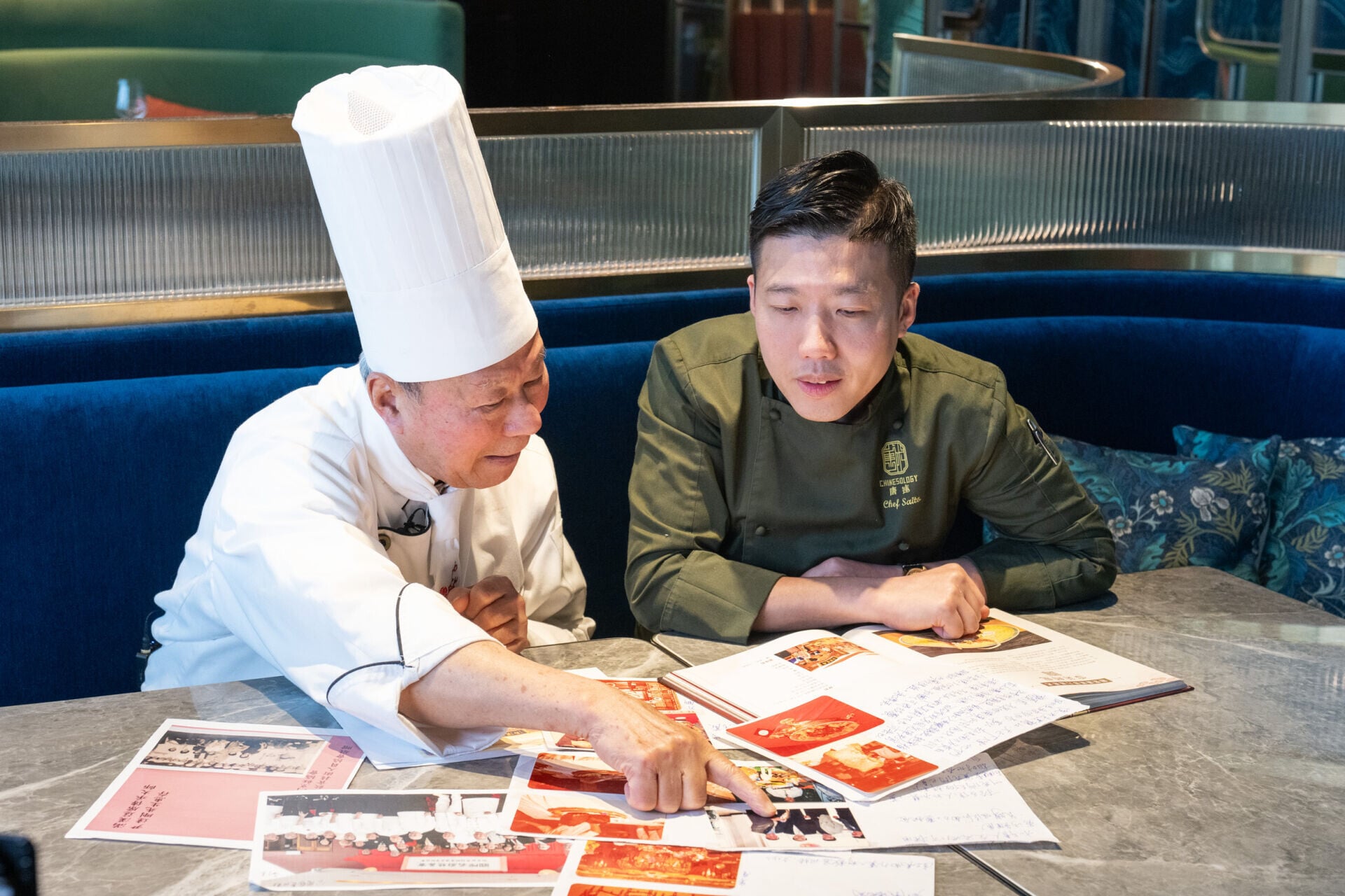 Master Wan (left) and Chef Saito Chau share the photos from the past 圖左尹達剛師傅和圖右周世韜師傅分享昔日相片