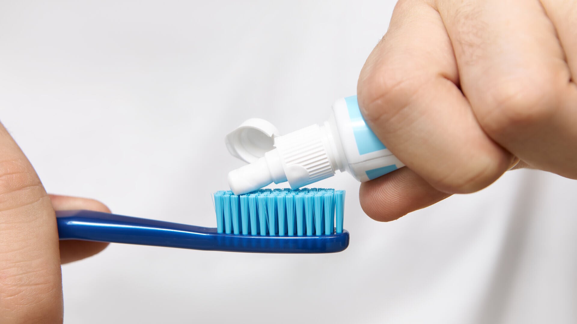 Close up image man s hands holding tube squeezing whitening toothpaste brush