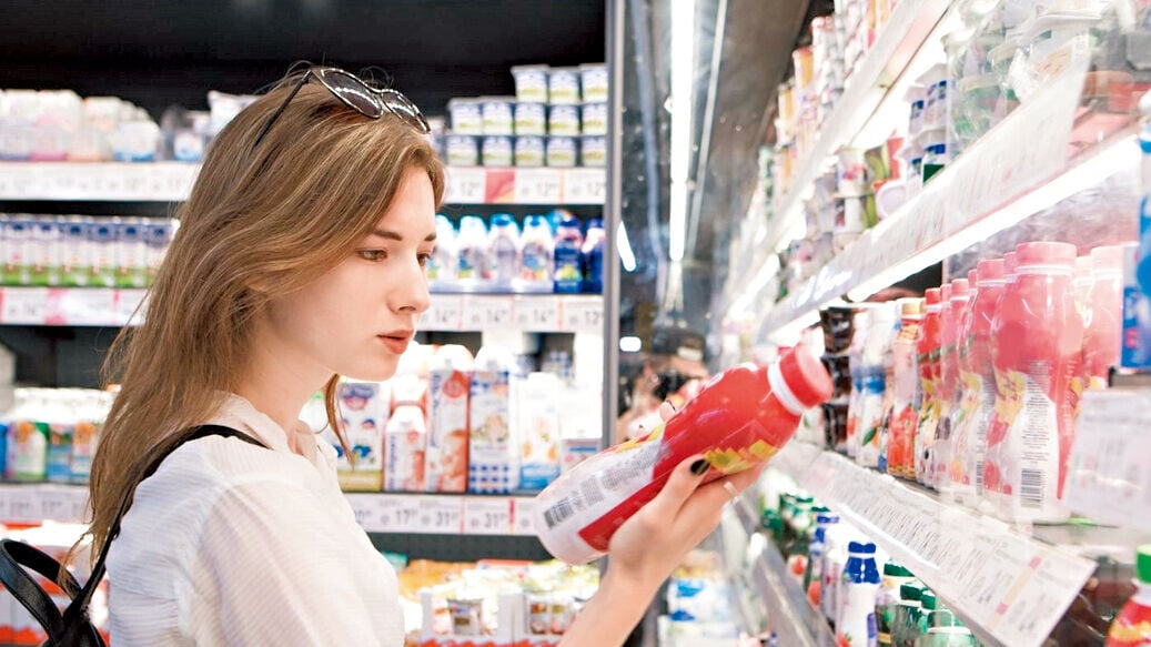 Health 3col chero  woman holding yogurt in shop reading label nutritional