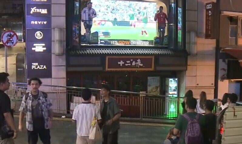 有街坊在德己立街及蘭桂坊交界這部大電視駐足觀看大電視。(Now新聞截圖)