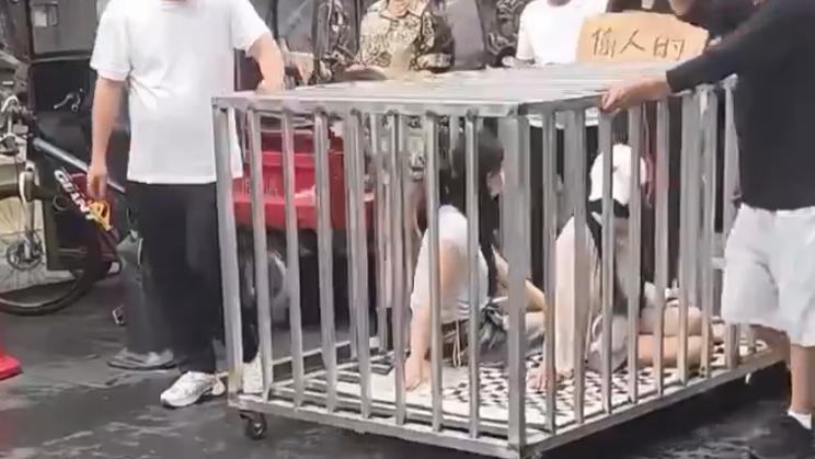 湖南岳陽汨羅市一街道鬥有多名男女當街拉人「浸豬籠」遊行，引發不少人圍觀拍攝。汨羅市公安局通報稱事件是擺拍，策劃組織者已被刑拘，另有8人被行政拘留。(影片截圖)