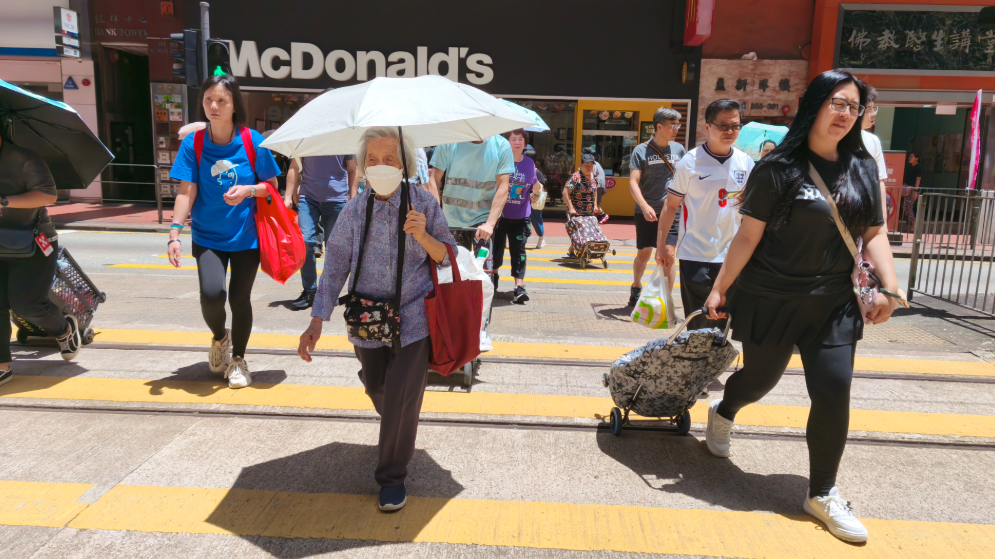 6月30日，香港市民在炎熱天氣下出行，天文台發出黃色工作暑熱警告。(中通社)