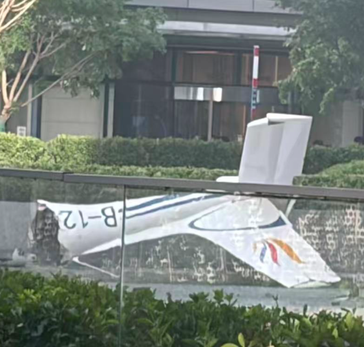 一架小型飛機撞上北京中信大廈後墜毀,大廈兩面玻璃破裂。該小型飛機則斷裂,部分殘骸掉落在大樓樓底和路面起火。(網上圖片/影片截圖)