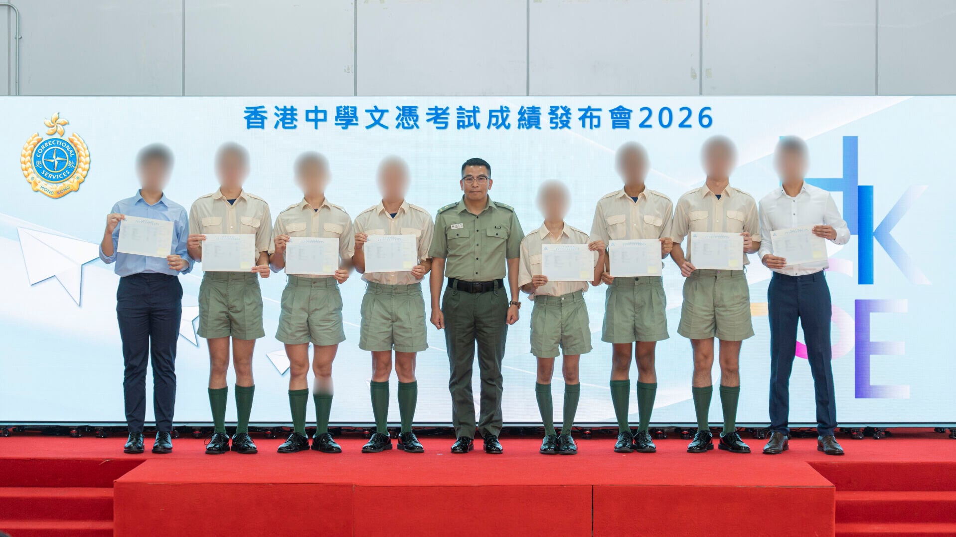圖示沙咀懲教所監督潘浩霖（中）向考生頒發成績通知書後，與他們合照。
