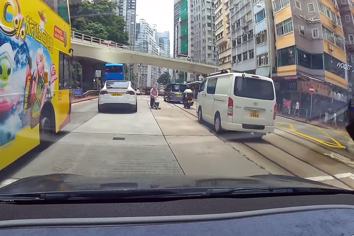 英皇道有一名推着四輪助行車的婆婆呆站路中,路過的南亞裔男子見狀把單車「閘停」的士,協助她安全離開馬路範圍。(網上影片截圖)