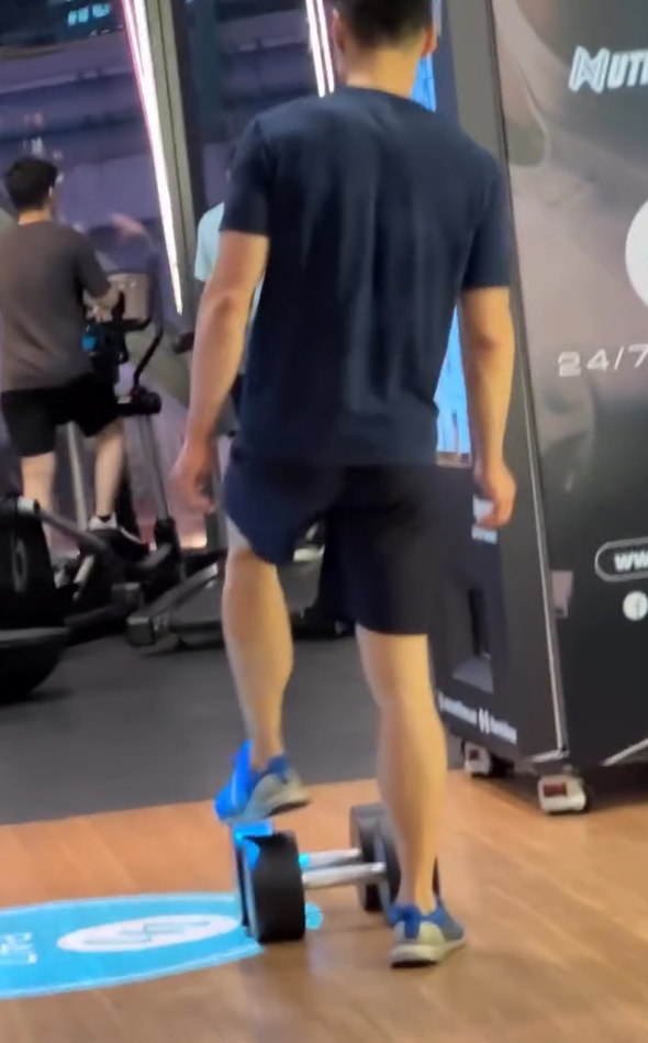 一名男顧客在一間連鎖健身中心「24/7 FITNESS」的銅鑼灣分店內,將一個重30kg的啞鈴用腳來回推動。(Threads)