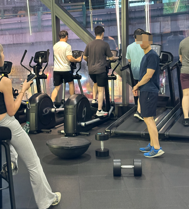 一名男顧客在一間連鎖健身中心「24/7 FITNESS」的銅鑼灣分店內,將一個重30kg的啞鈴用腳來回推動。(Threads)