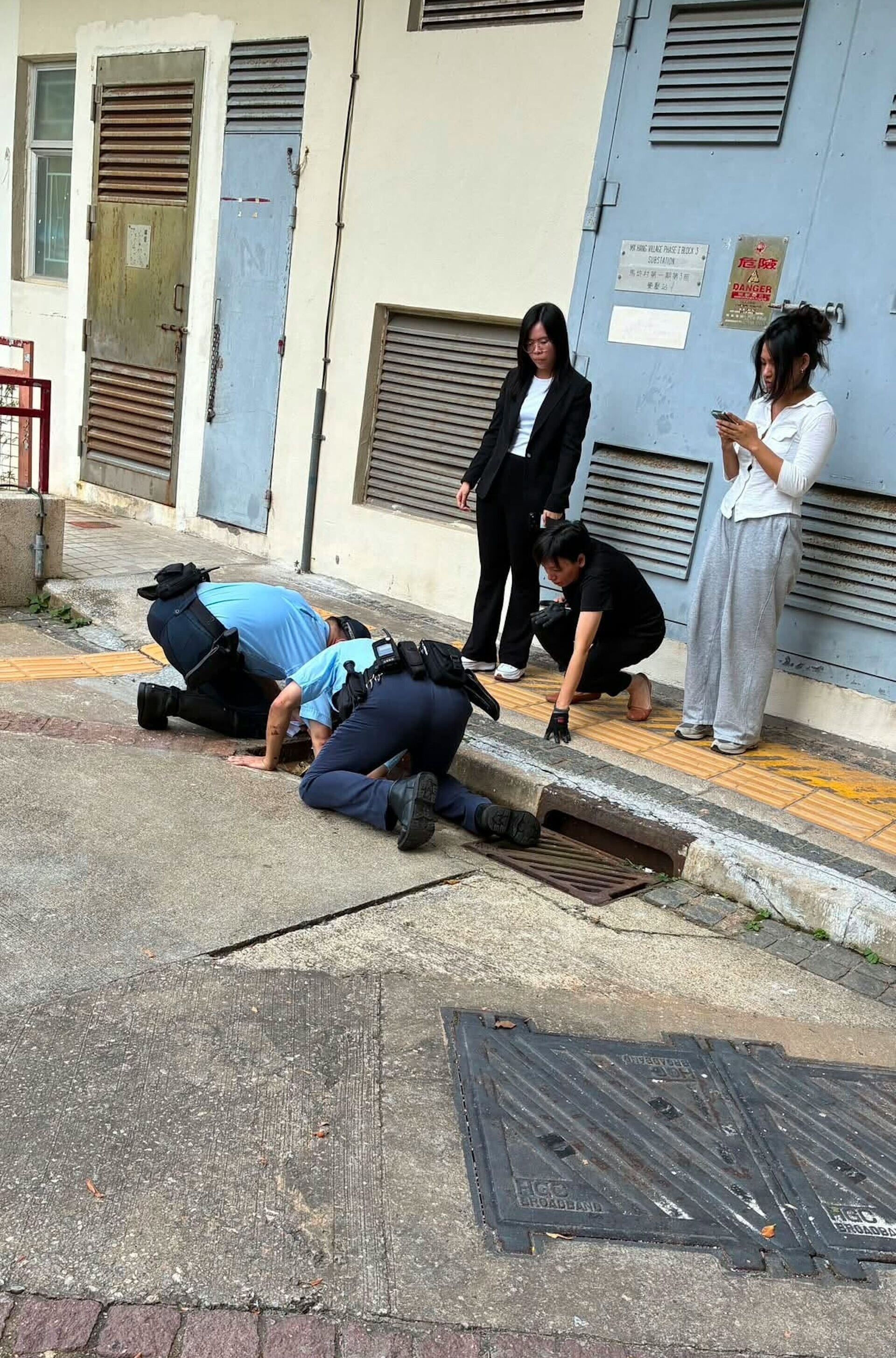 數名警員與消防員伏在渠口,嘗試尋找貓咪蹤影。(FB/赤柱街坊八1八(Stanley 818))