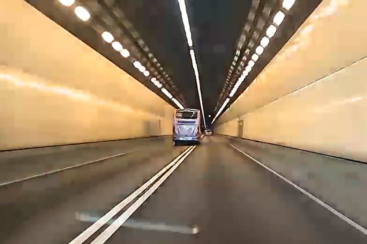 城門隧道一輛旅遊巴懷疑71歲司機病發暈倒,撞向路旁石壆始停下。(網上影片截圖)