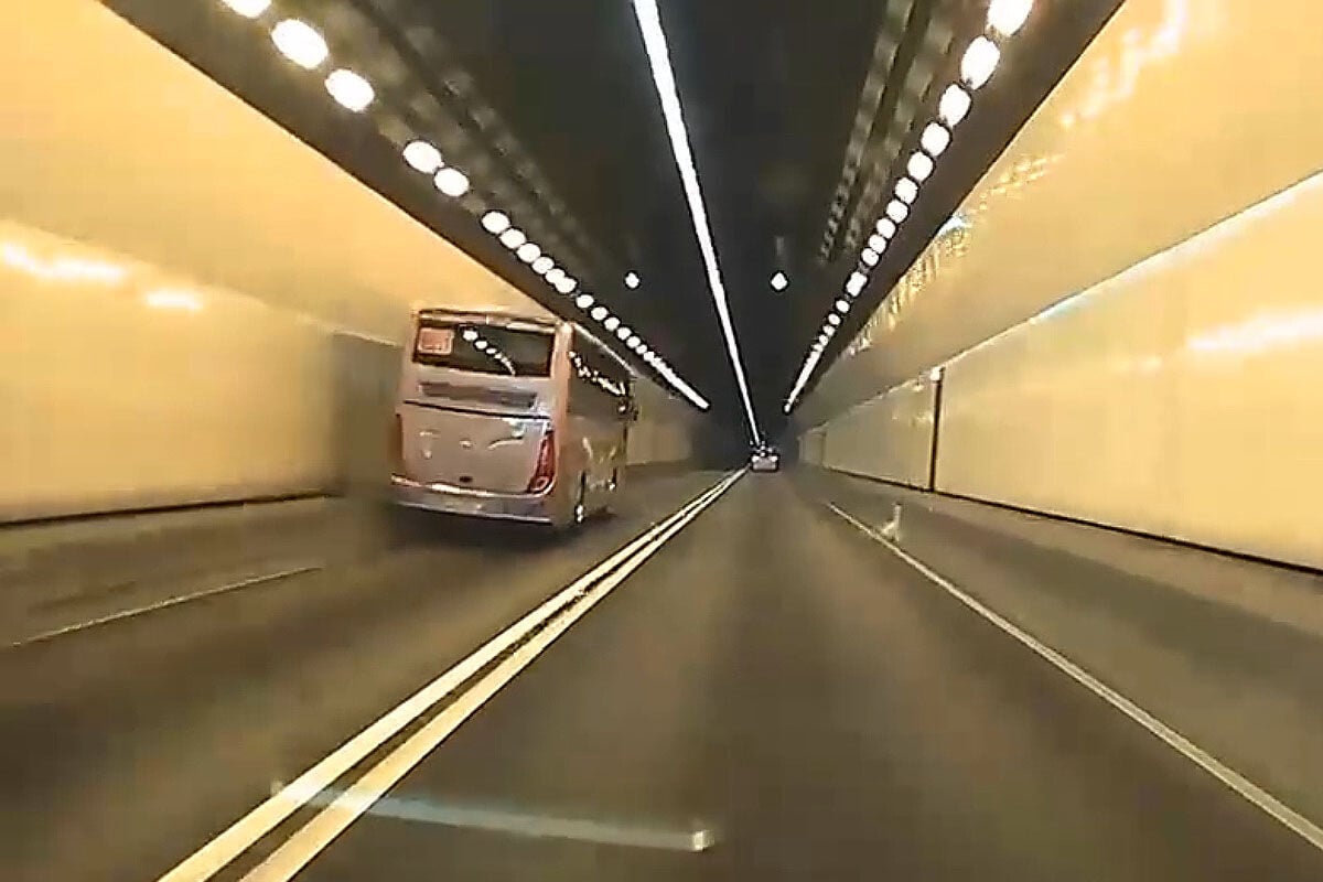 城門隧道一輛旅遊巴懷疑71歲司機病發暈倒,撞向路旁石壆始停下。(網上影片截圖)