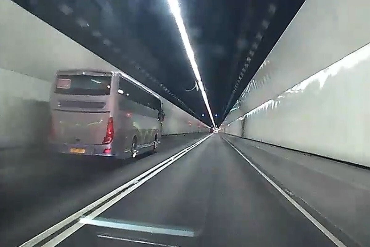 城門隧道一輛旅遊巴懷疑71歲司機病發暈倒,撞向路旁石壆始停下。(網上影片截圖)