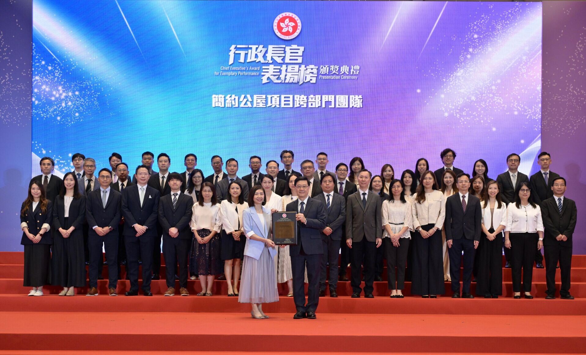 行政長官李家超在「行政長官表揚榜」頒獎典禮上向「簡約公屋項目跨部門團隊」頒授獎狀。圖示李家超(前排右)向時任房屋局副秘書長(特別職務)王明慧(前排左)頒授獎狀。