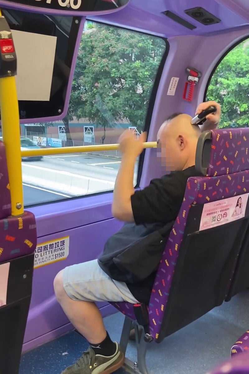 一名男子在巴士車廂內,旁若無人地用電剪修剪頭髮。(網上影片截圖)