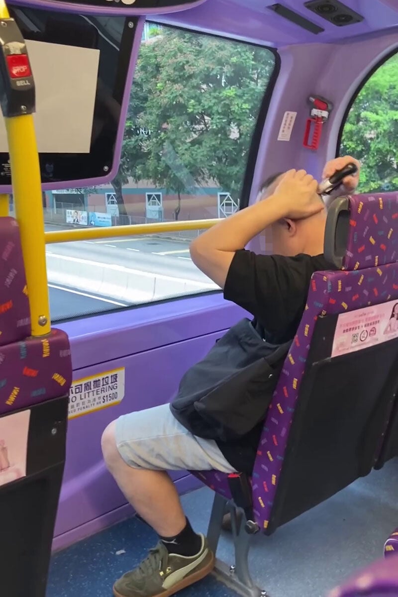 一名男子在巴士車廂內,旁若無人地用電剪修剪頭髮。(網上影片截圖)