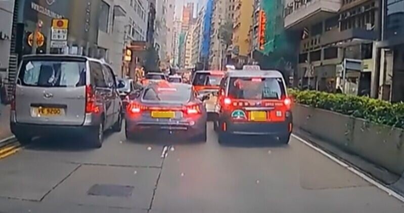 私家車騎行於兩條行車線中間行駛,貼近的士前行,疑似想以車身逼使的士讓位。(FB/車cam L(香港群組))
