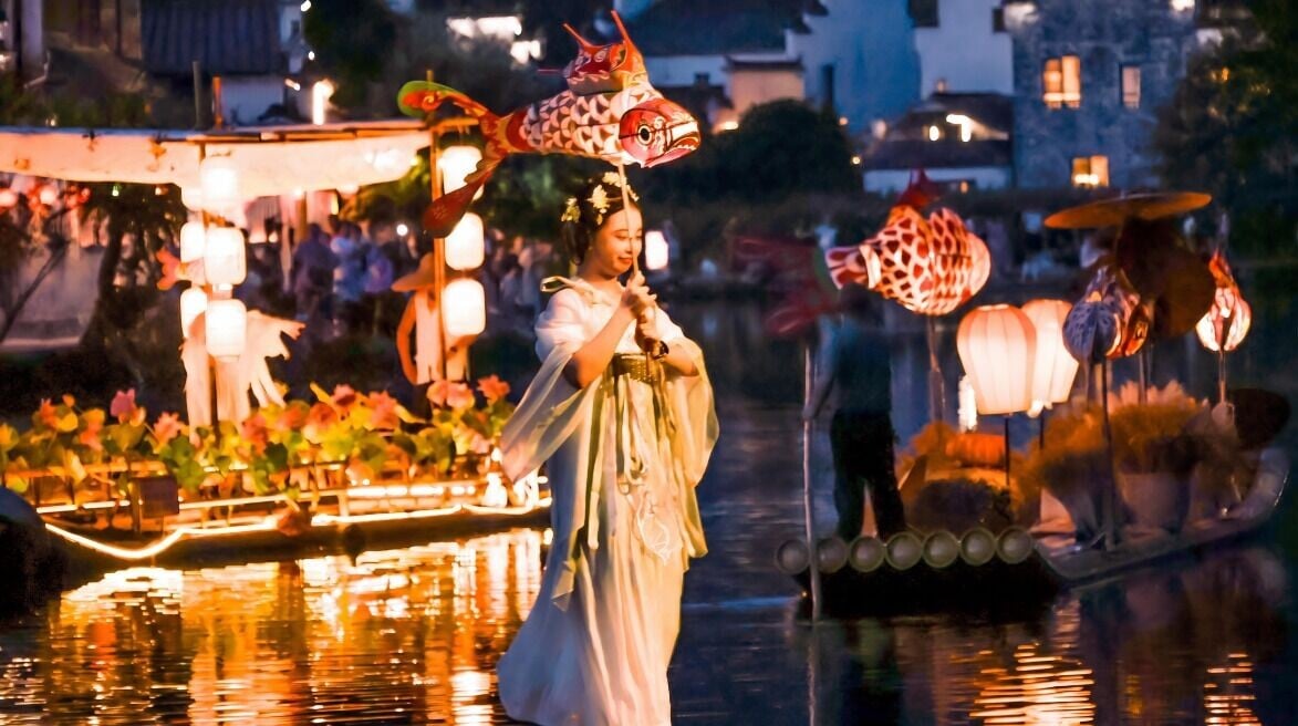 在呈坎古村,除了欣賞魚燈巡遊,遊客也可以提着自己做的小魚燈跟在隊伍裏,邊走邊摸魚燈求好運。(圖片來源:視覺中國)