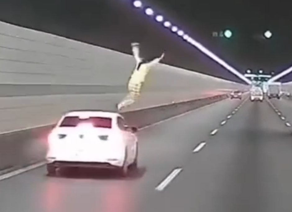 浙江錢江隧道一輛私家車在隧道內行駛期間,副駕駛座一名女子突然爬出車窗,站上車頂後突跳下,鄰線後方一輛大型貨車緊急避讓。(影片截圖)