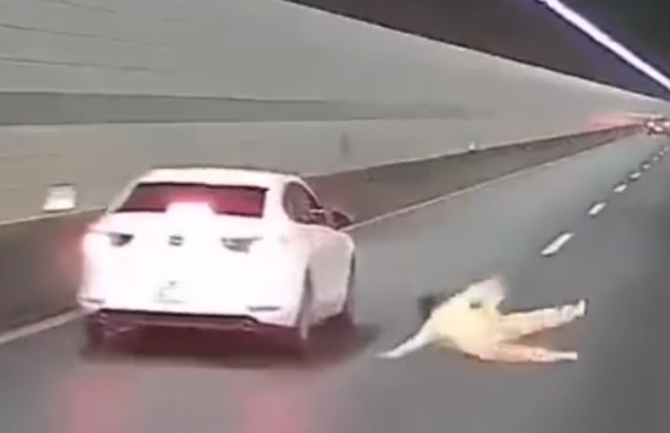 浙江錢江隧道一輛私家車在隧道內行駛期間,副駕駛座一名女子突然爬出車窗,站上車頂後突跳下,鄰線後方一輛大型貨車緊急避讓。(影片截圖)