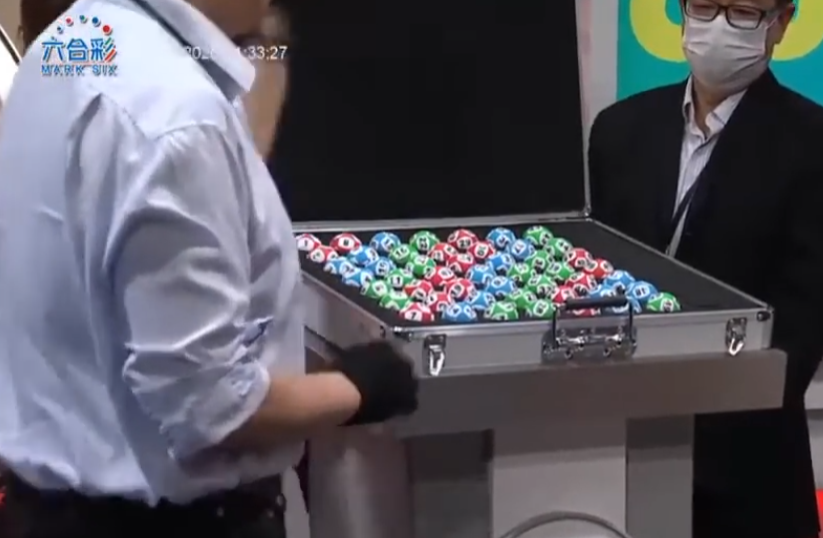 六合彩攪珠機出現罕見故障,沒有號碼球掉落中間管道,須改用後備攪珠機及後備號碼,並由監場嘉賓監察更換過程。(直播畫面)
