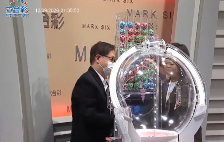 六合彩攪珠機出現罕見故障,沒有號碼球掉落中間管道,須改用後備攪珠機及後備號碼,並由監場嘉賓監察更換過程。(直播畫面)