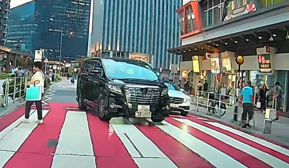 一輛掛兩地牌的七人車駛至啟德沐翠街晴朗商場對開一條斑馬線時疑「趕時間」,突然扭軚切出逆線「爬頭」強行橫越斑馬線。(車cam L(香港群組)fb)