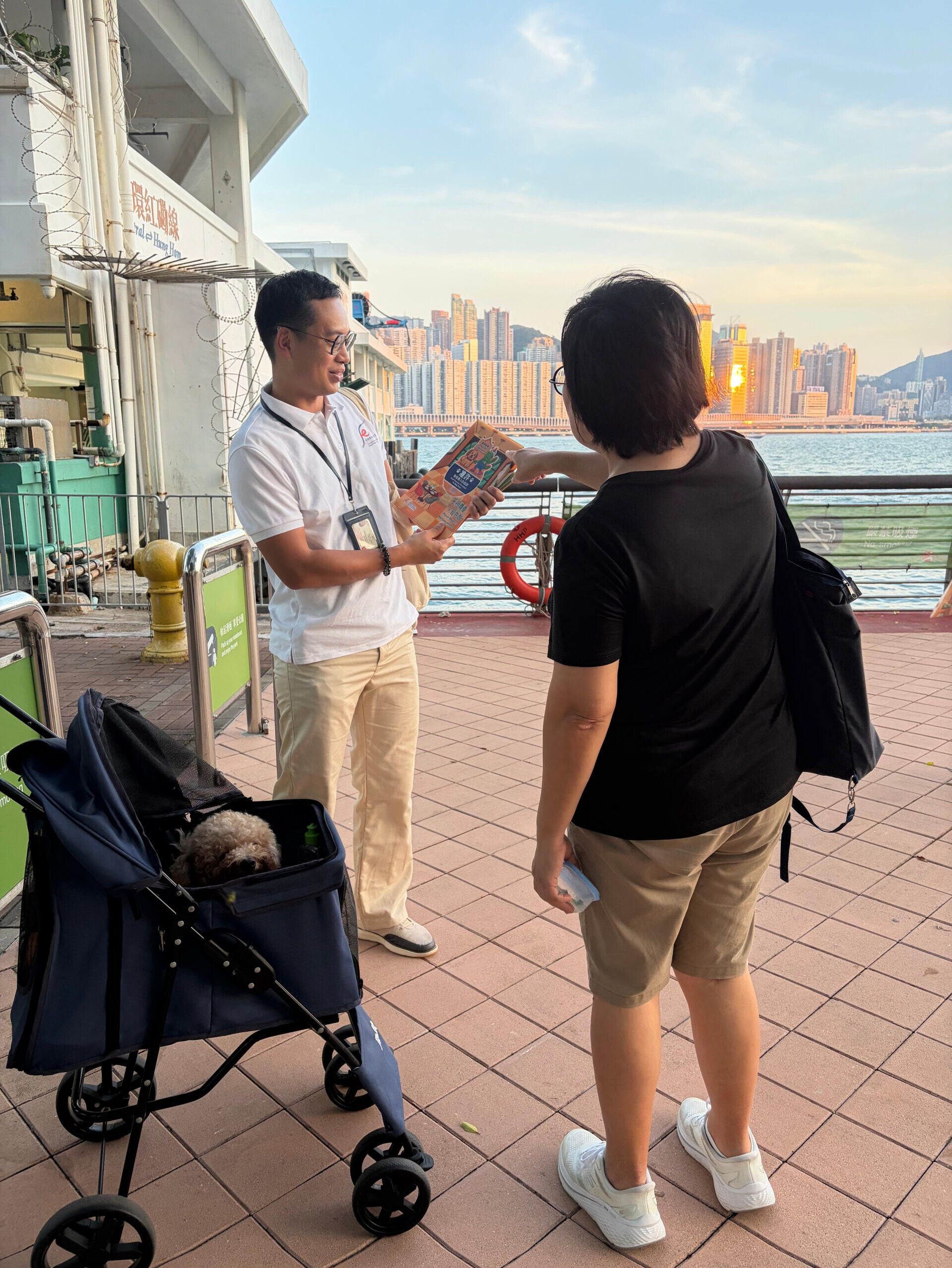 圖示食環署人員向狗主派發宣傳單張,提醒他們攜狗外出用膳時須守法依規。(政府新聞處)
