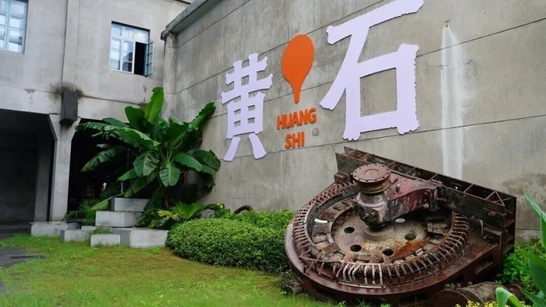 鏽跡斑斑的工業機械零件依偎在「黃石」地標牆前,成了遊客心照不宣的標準打卡公式。(圖片來源:華新1907文化公園服務號)