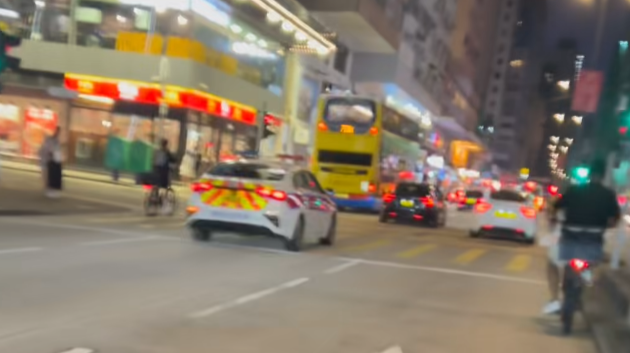 油麻地一名疑是外賣員的非華裔男子駕駛電動單車沿快線行駛，中線有一輛警車，慢線亦有另一名疑是外賣員的男子駕駛電動單車。(「車cam L（香港群組）」fb)