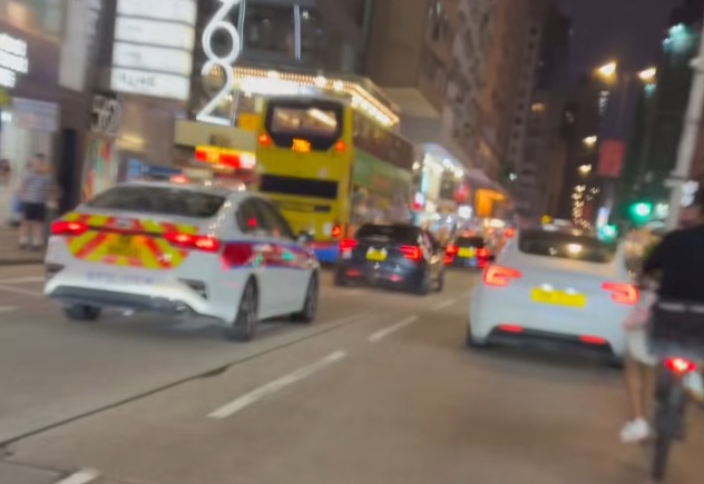 油麻地一名疑是外賣員的非華裔男子駕駛電動單車沿快線行駛,中線有一輛警車,慢線亦有另一名疑是外賣員的男子駕駛電動單車。(「車cam L(香港群組)」fb)