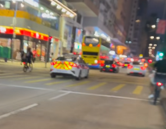 油麻地一名疑是外賣員的非華裔男子駕駛電動單車沿快線行駛,中線有一輛警車,慢線亦有另一名疑是外賣員的男子駕駛電動單車。(「車cam L(香港群組)」fb)
