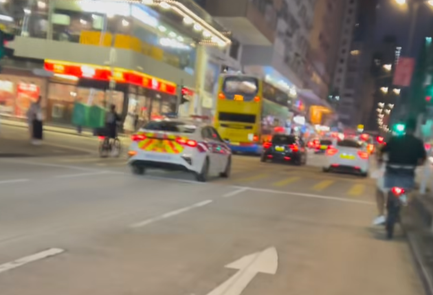油麻地一名疑是外賣員的非華裔男子駕駛電動單車沿快線行駛,中線有一輛警車,慢線亦有另一名疑是外賣員的男子駕駛電動單車。(「車cam L(香港群組)」fb)