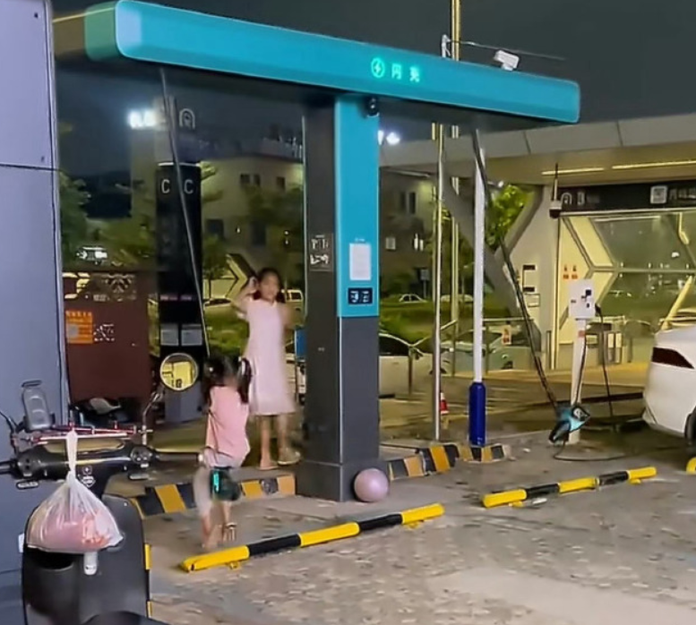 多名女童在廣西南寧一個汽車充電站,把高壓充電槍的電纜當鞦韆擺盪。(影片截圖)
