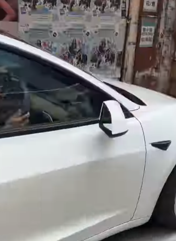 一輛Tesla電動車沿灣仔菲林明道30號外的行人路上倒車(Threads)