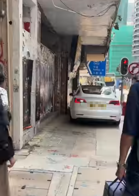 一輛Tesla電動車沿灣仔菲林明道30號外的行人路上倒車(Threads)