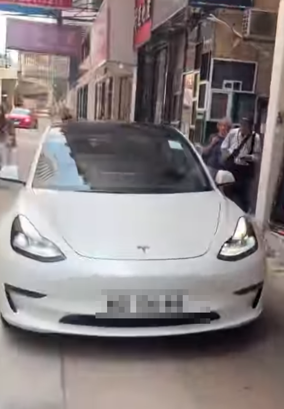 一輛Tesla電動車沿灣仔菲林明道30號外的行人路上倒車(Threads)