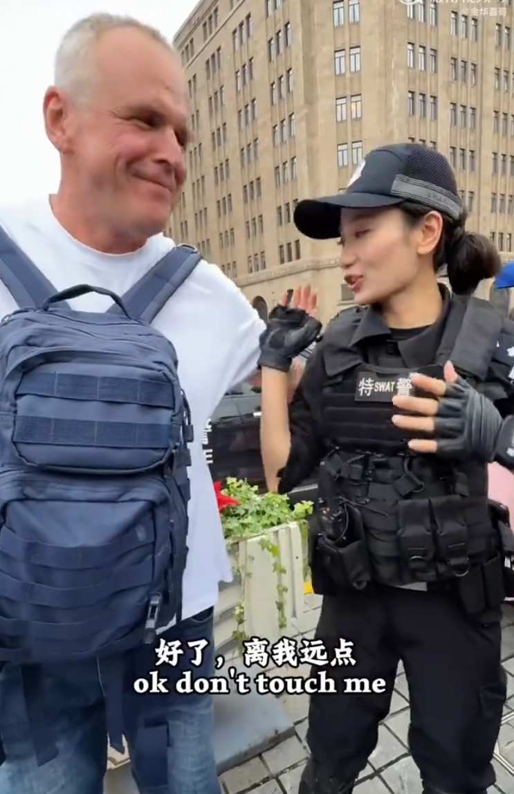 上海外灘外籍遊客向女特警錢雪穎提出合照請求時,伸手欲摟抱肩膀。她提醒「Don’t touch me」令該名遊客縮手。(影片截圖)